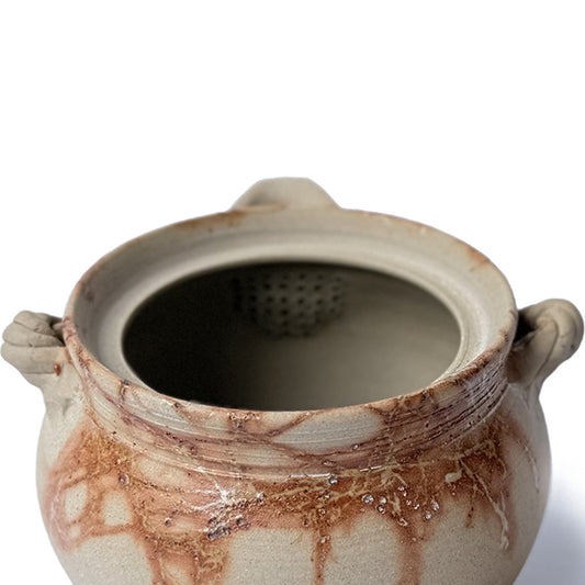 Closeup of a Ceramic teapot with built-in strainer on a white background