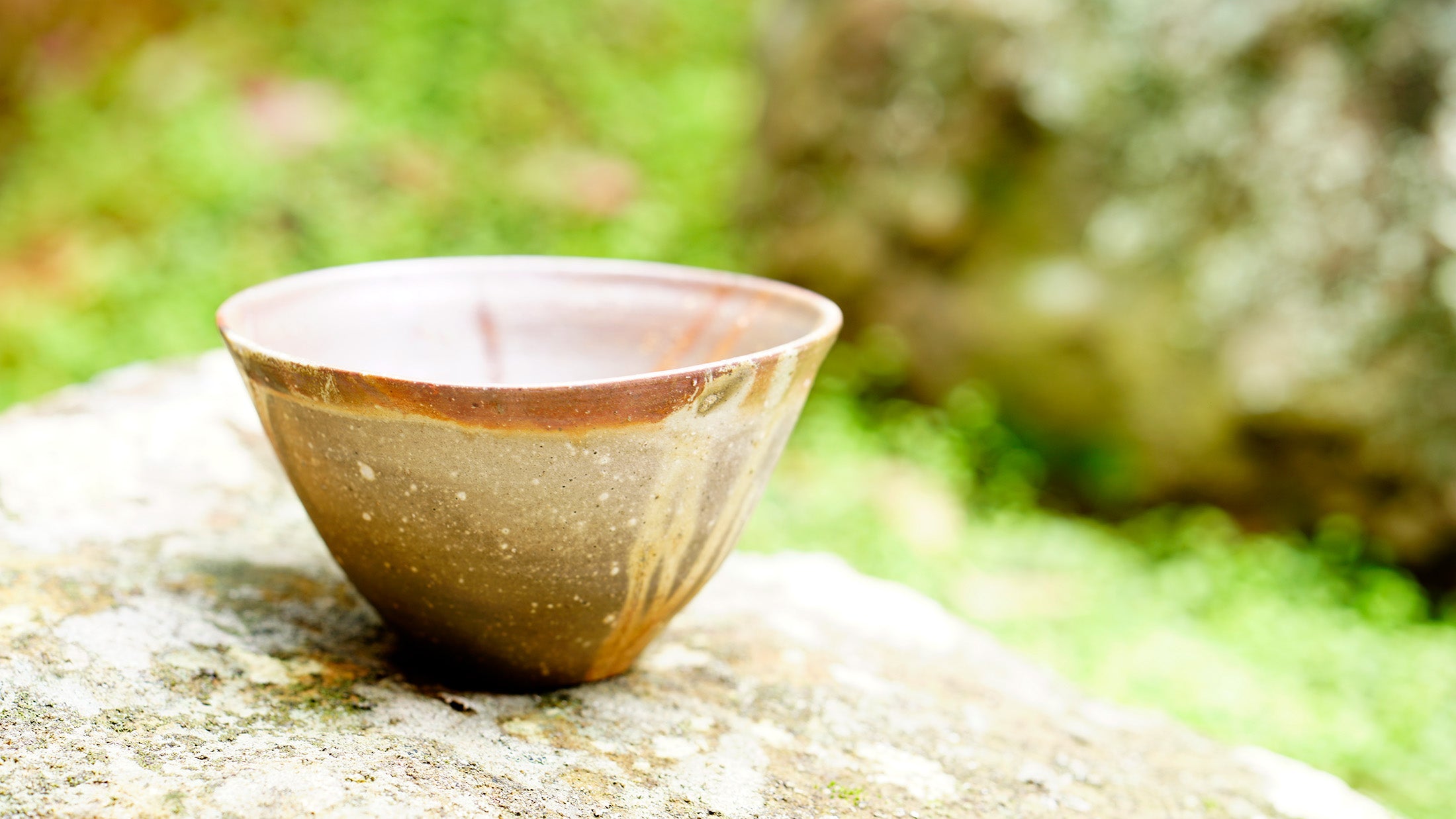 HIDASUKI chawan sits on a rock with nature in background