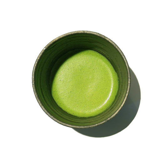Vibrant Green KIR matcha inside on a matcha bowl on white background