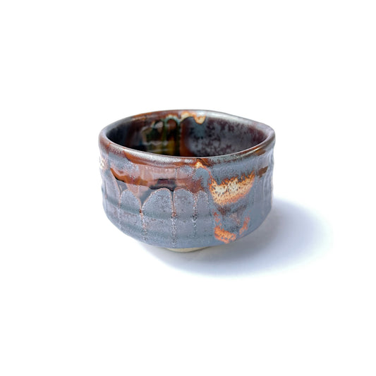 A hand-thrown, half-cylindrical, gray and brown glazed KOHAKU ceramic matcha bowl with a flat bottom, isolated on a white background.