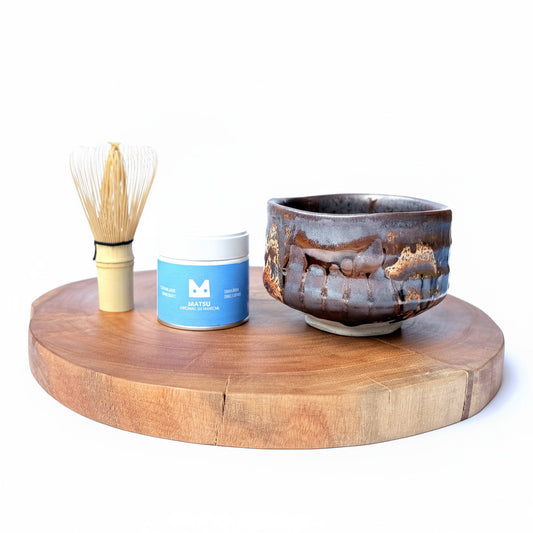 Matcha bowl, bamboo whisk and AOI matcha can on a wooden stand with a white background