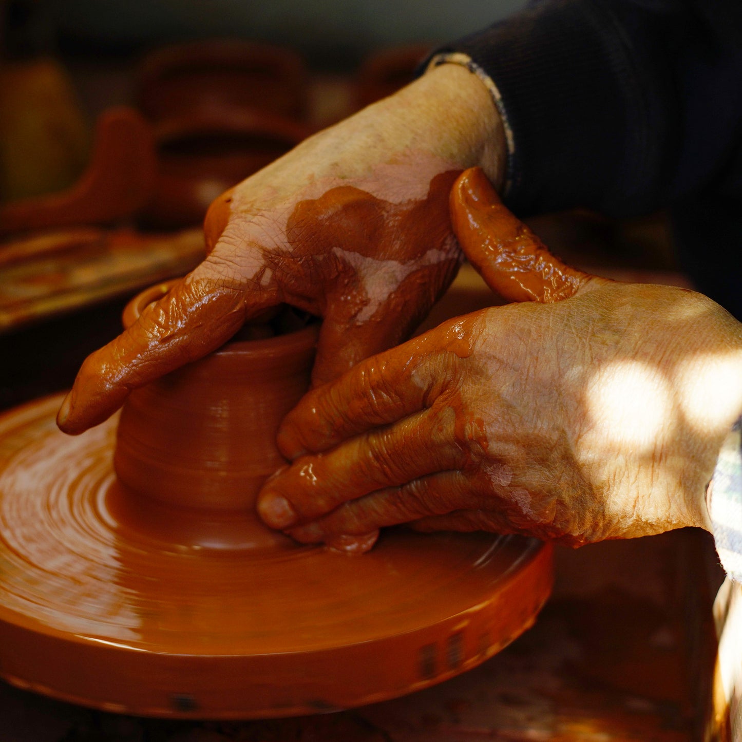 Hands working with clay on a potter's wheel