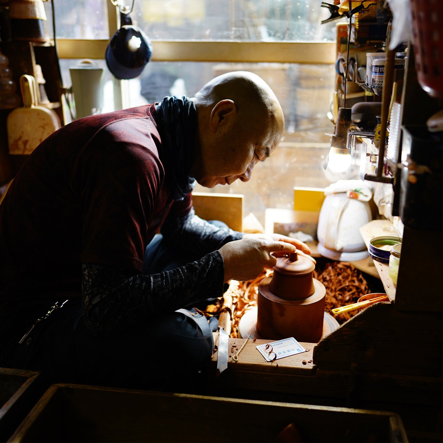 Artist working with teapot lid on a pottery wheel in a workshop