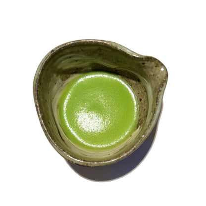 Vibrant green AOI matcha powder whisked in a matcha bowl with spout, showcasing its rich colour and smooth texture