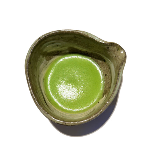 Vibrant green AOI matcha powder whisked in a matcha bowl with spout, showcasing its rich colour and smooth texture