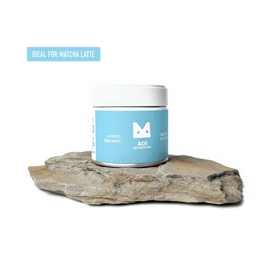 AOI matcha powder in a white can on a rock labeled 'Ideal for matcha latte'