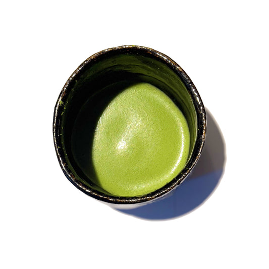 Vibrant green MATSU matcha powder whisked in a matcha bowl, showcasing its smooth texture and bright color