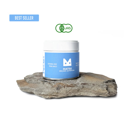 Matsu Organic Matcha container on a rock with a visible brand logo.
