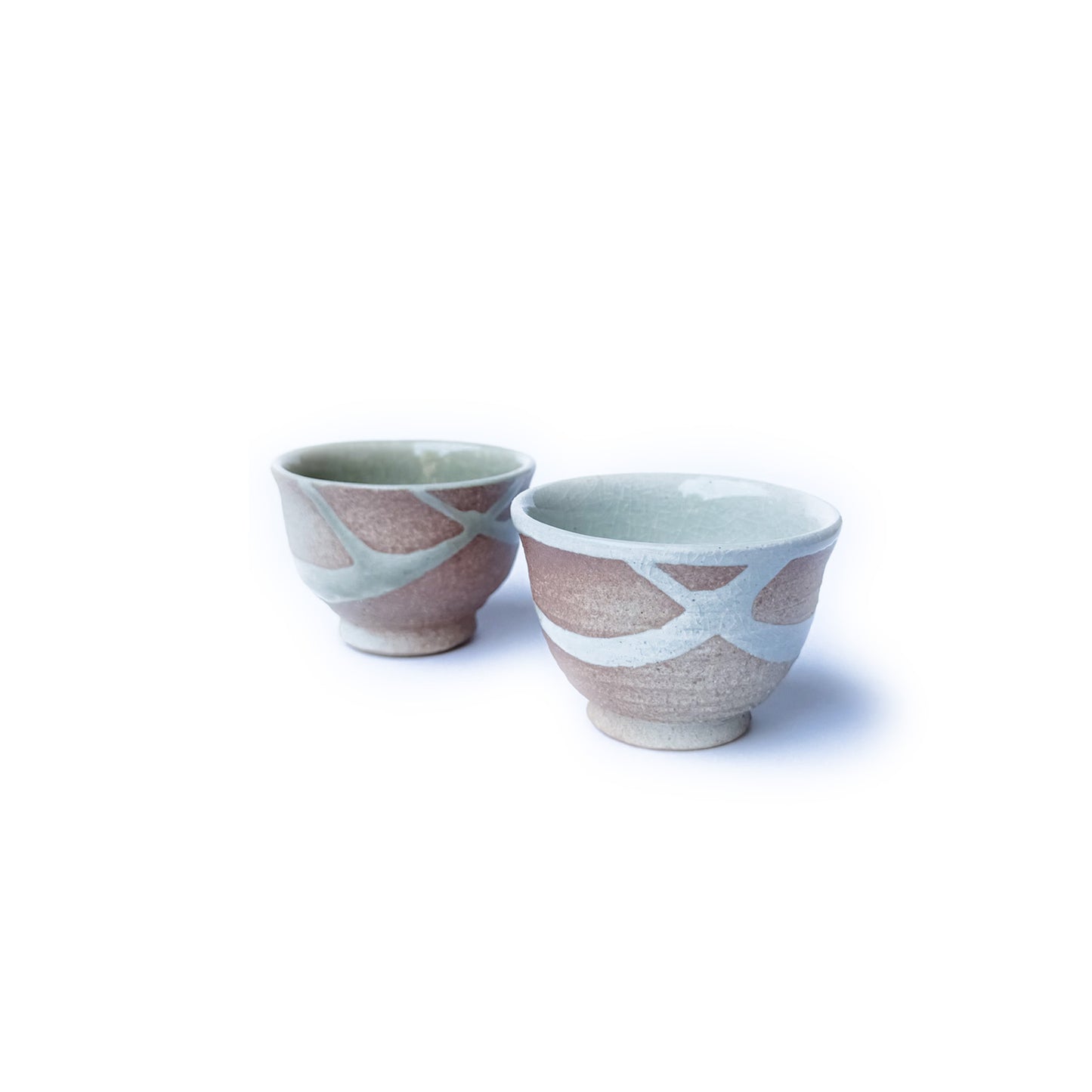 Two ceramic cups with abstract patterns on a white background