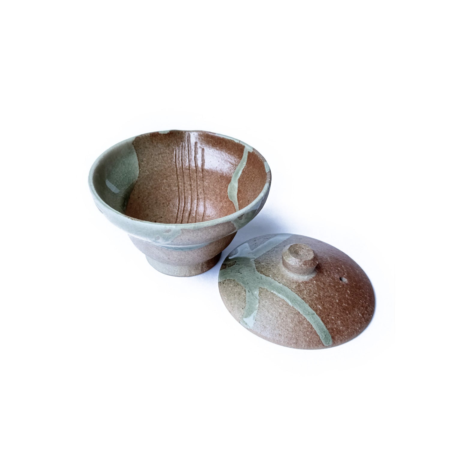 Ceramic Shiboridashi and lid with brown and green glaze on a white background